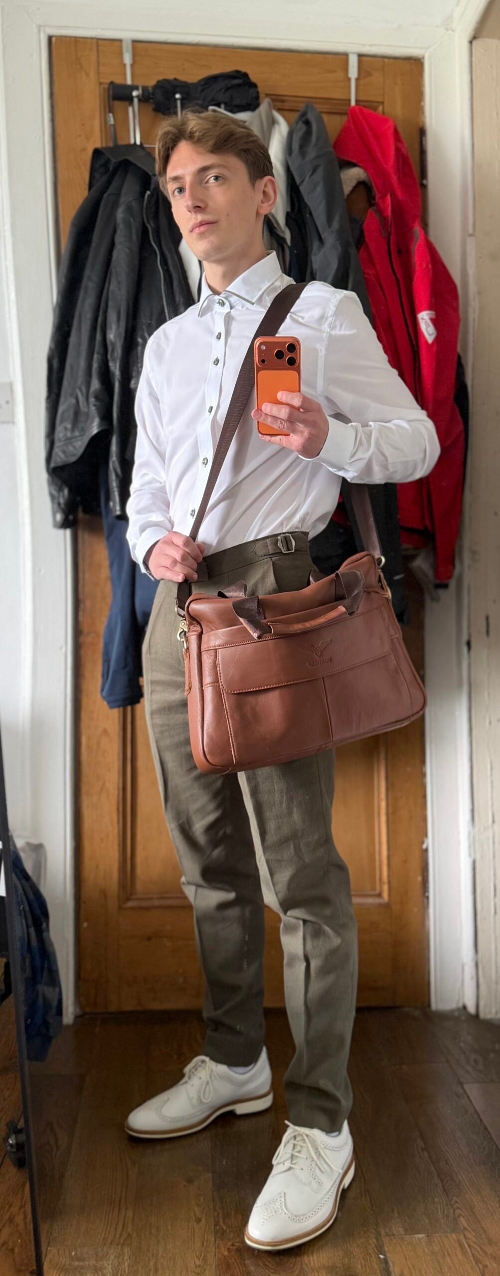 Man in smart-casual outfit holding a large leather bag.